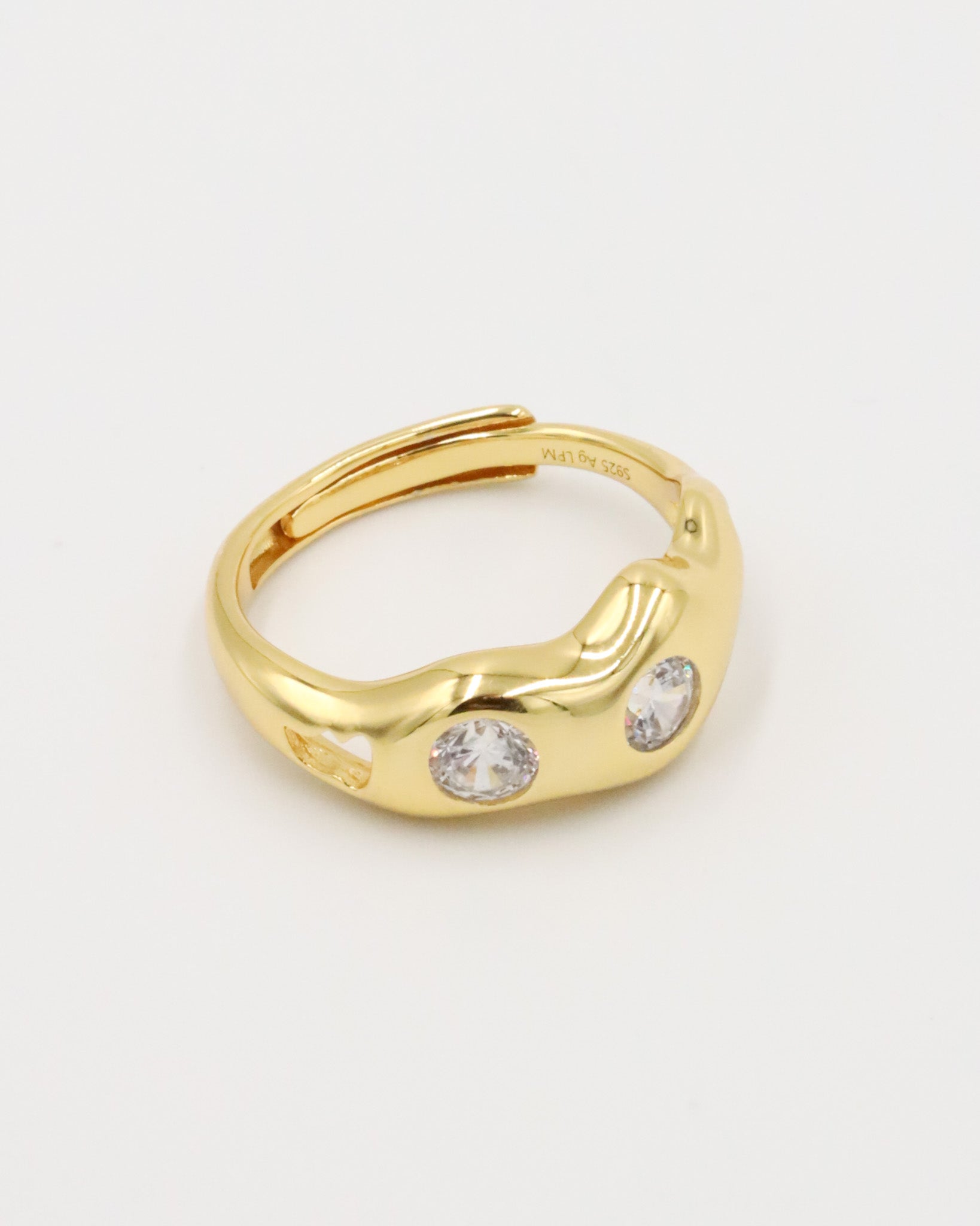 A gold-colored ring with two clear stones set in a wave-like design.
