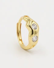 A gold-colored ring with two clear stones set in a wave-like design.