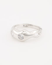 A silver-colored ring with two clear stones set in a wave-like design.