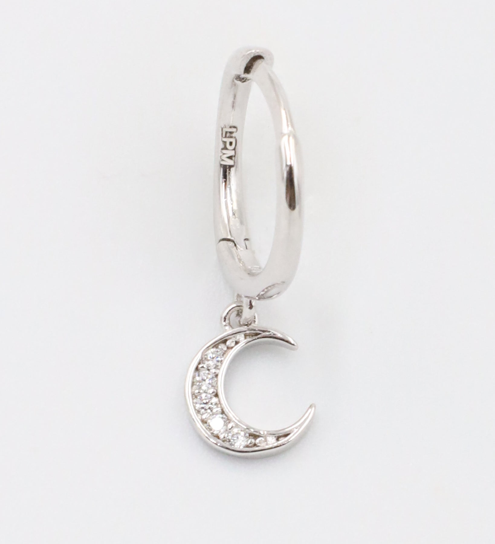 A silver hoop earring with a crescent moon charm attached, displayed against a white background.