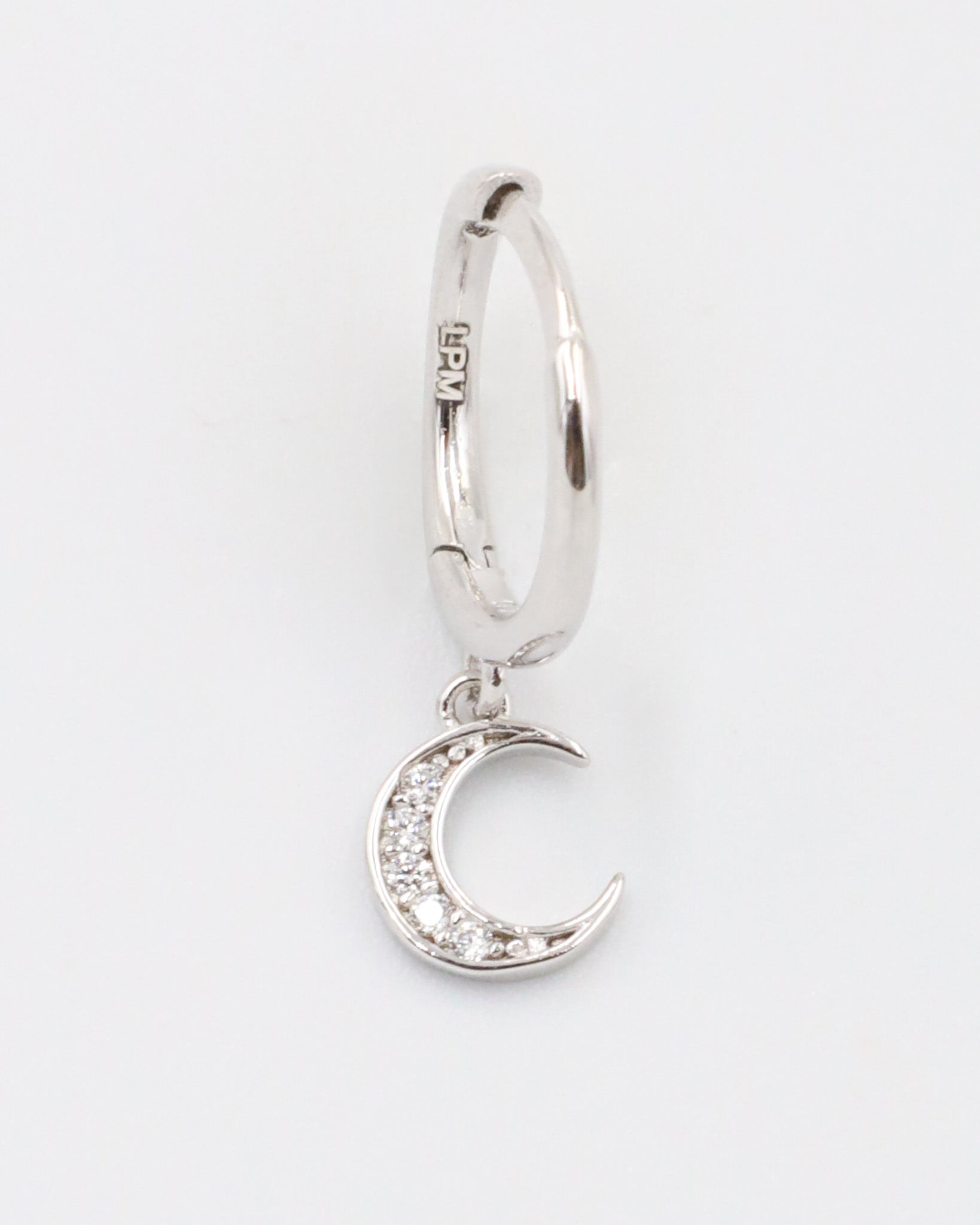 A silver hoop earring with a crescent moon charm attached, displayed against a white background.
