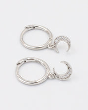 A silver hoop earring with a crescent moon charm attached, displayed against a white background.