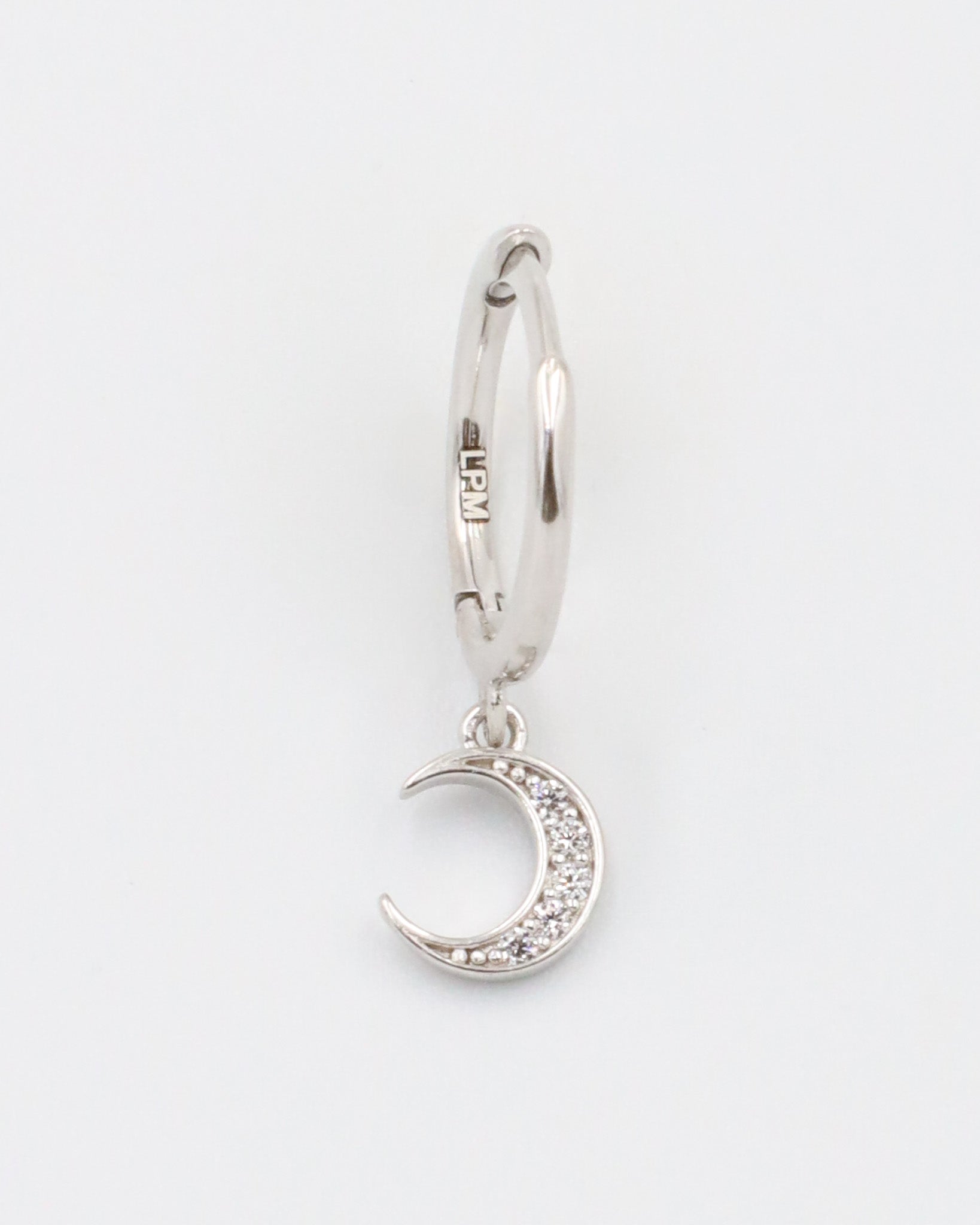 A silver hoop earring with a crescent moon charm attached, displayed against a white background.