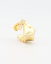Gold ear cuff on a light gray background