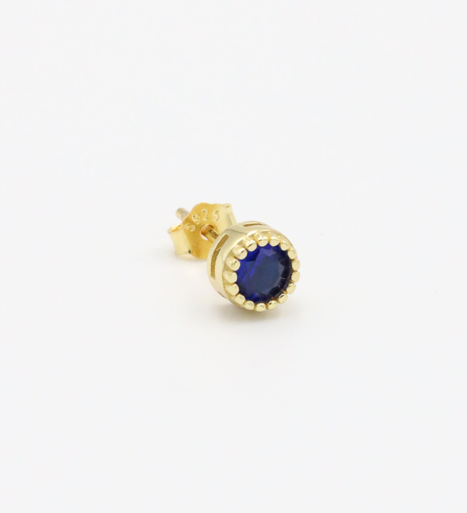 A single gold-colored stud earring with a blue stone and butterfly clasp closure on a white background.