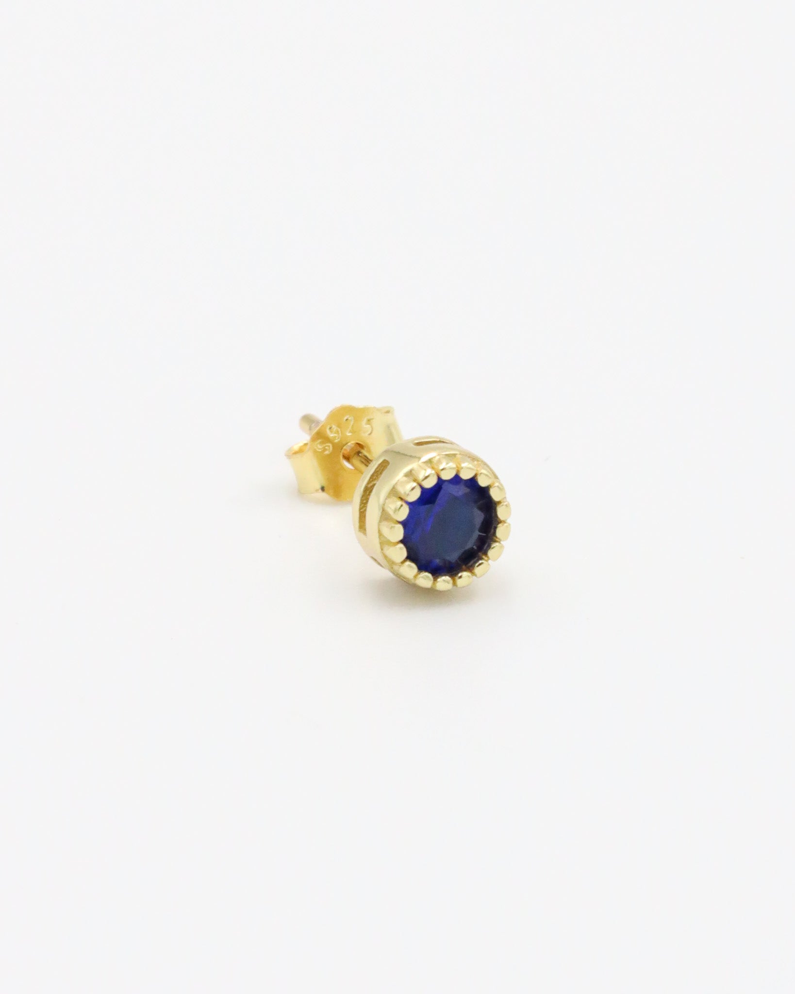 A single gold-colored stud earring with a blue stone and butterfly clasp closure on a white background.