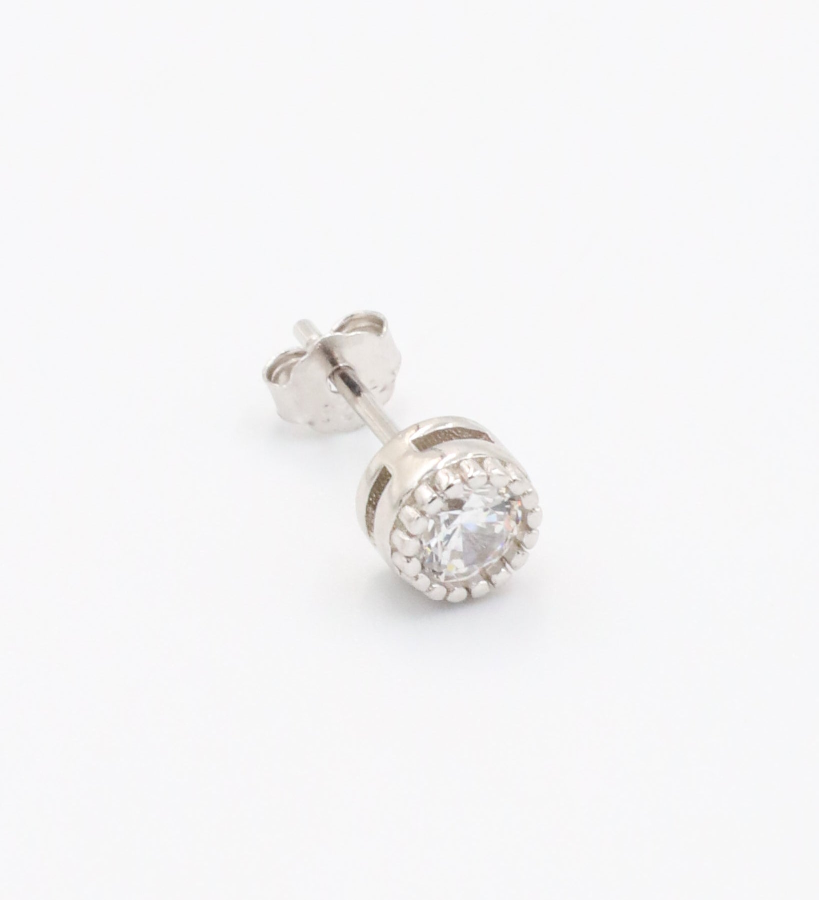 A single silver stud earring with a butterfly clasp and small clear stones arranged in a circular pattern around the central stone.