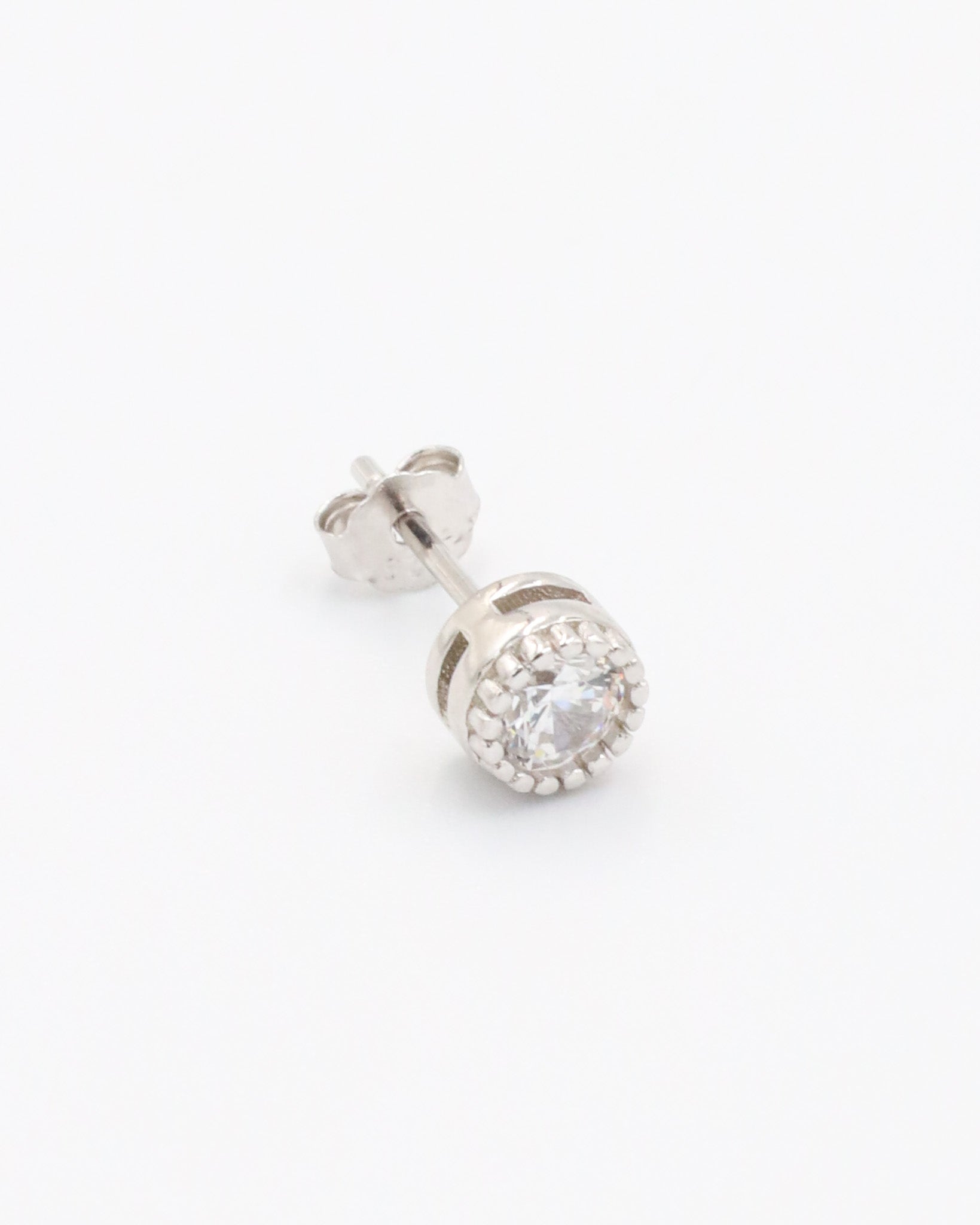 A single silver stud earring with a butterfly clasp and small clear stones arranged in a circular pattern around the central stone.