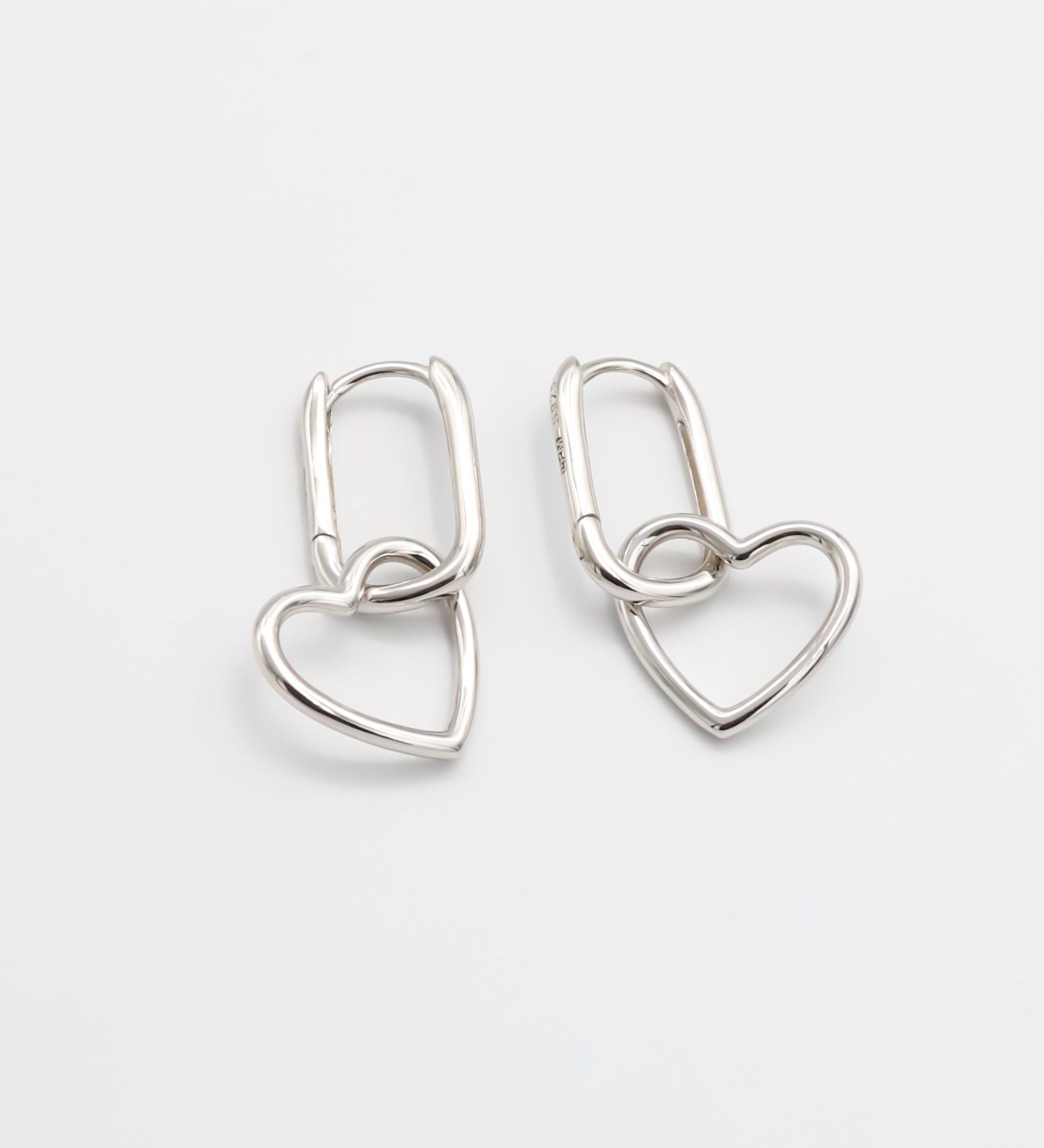 A pair of silver hoop earrings with a hinged clasp mechanism on a white background.