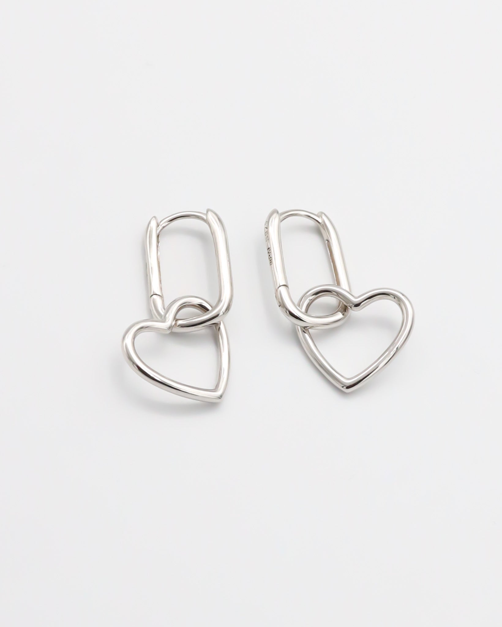 A pair of silver hoop earrings with a hinged clasp mechanism on a white background.