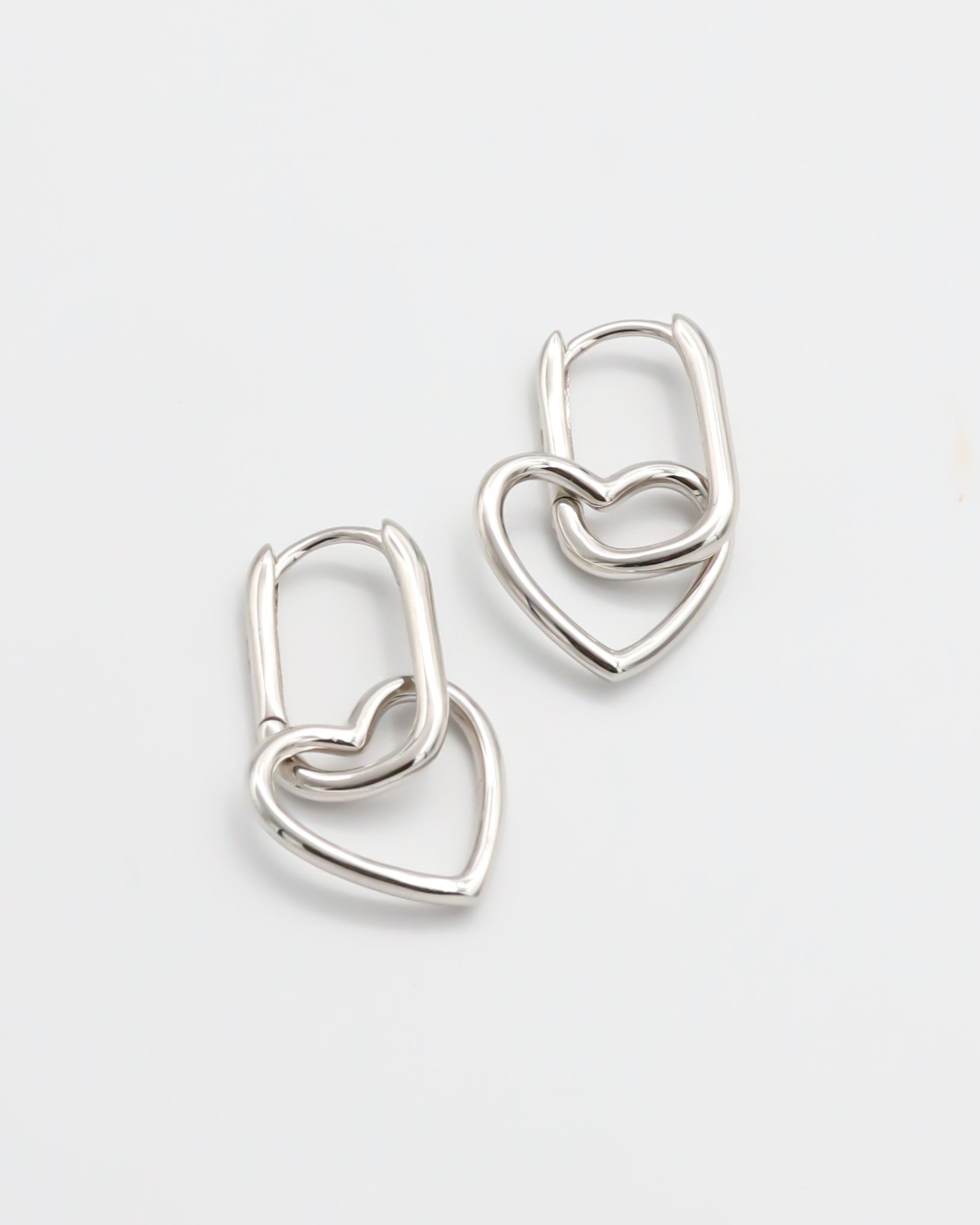 A pair of silver hoop earrings with a hinged clasp mechanism on a white background.
