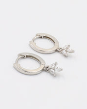 A silver-colored hoop earring with a hinged clasp and a dangling decorative element.