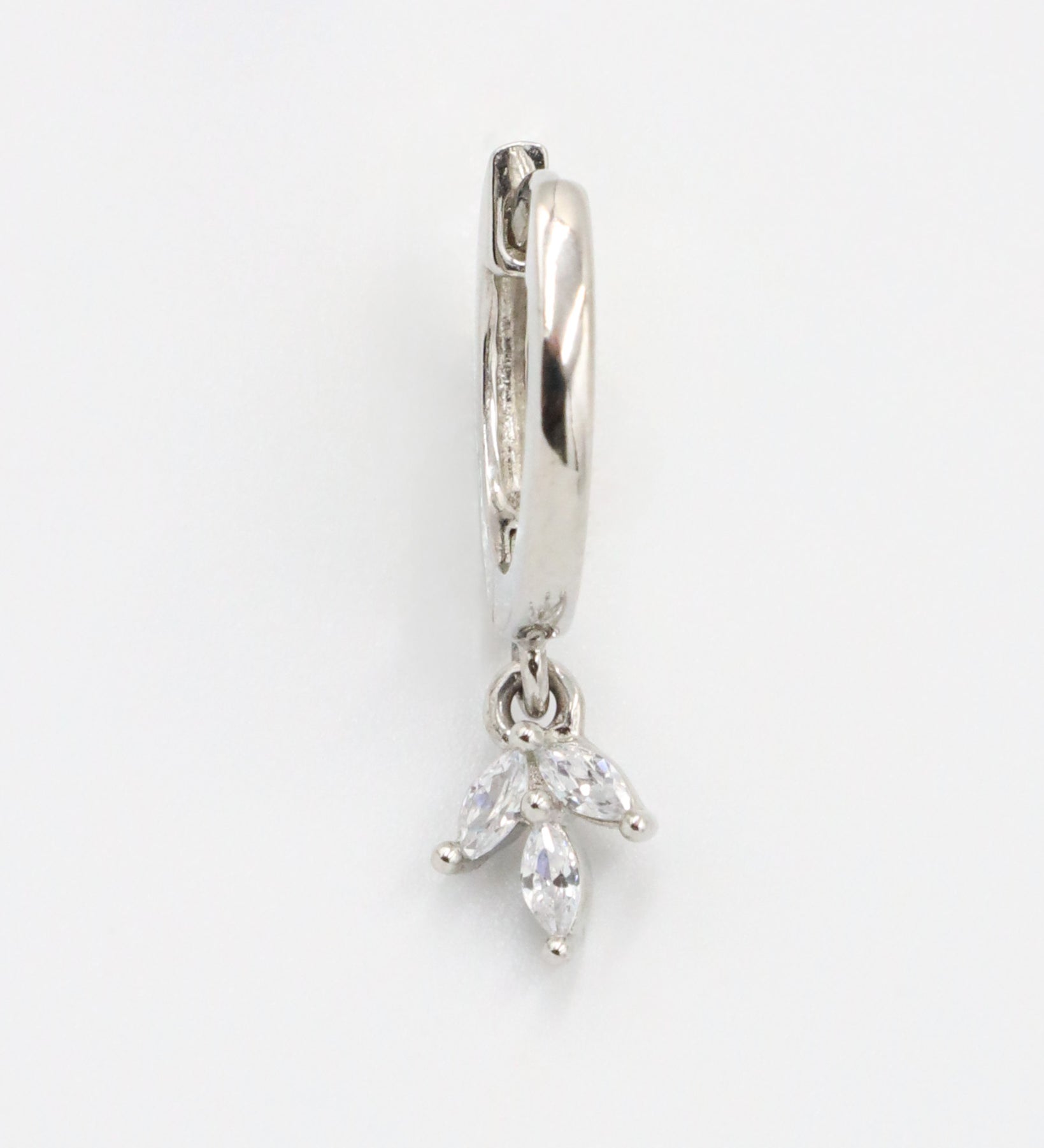 A silver-colored hoop earring with a hinged clasp and a dangling decorative element.