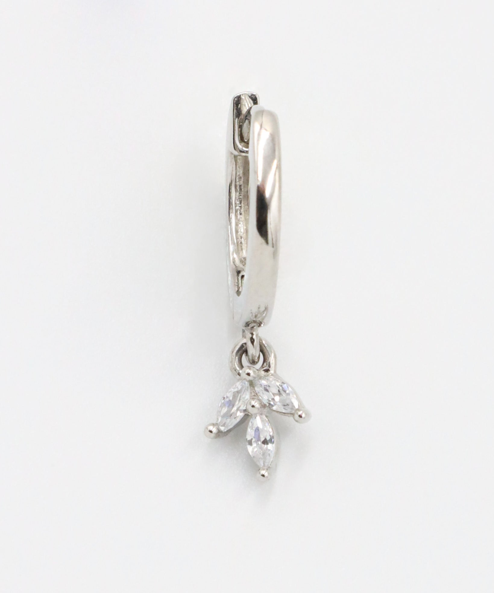 A silver-colored hoop earring with a hinged clasp and a dangling decorative element.