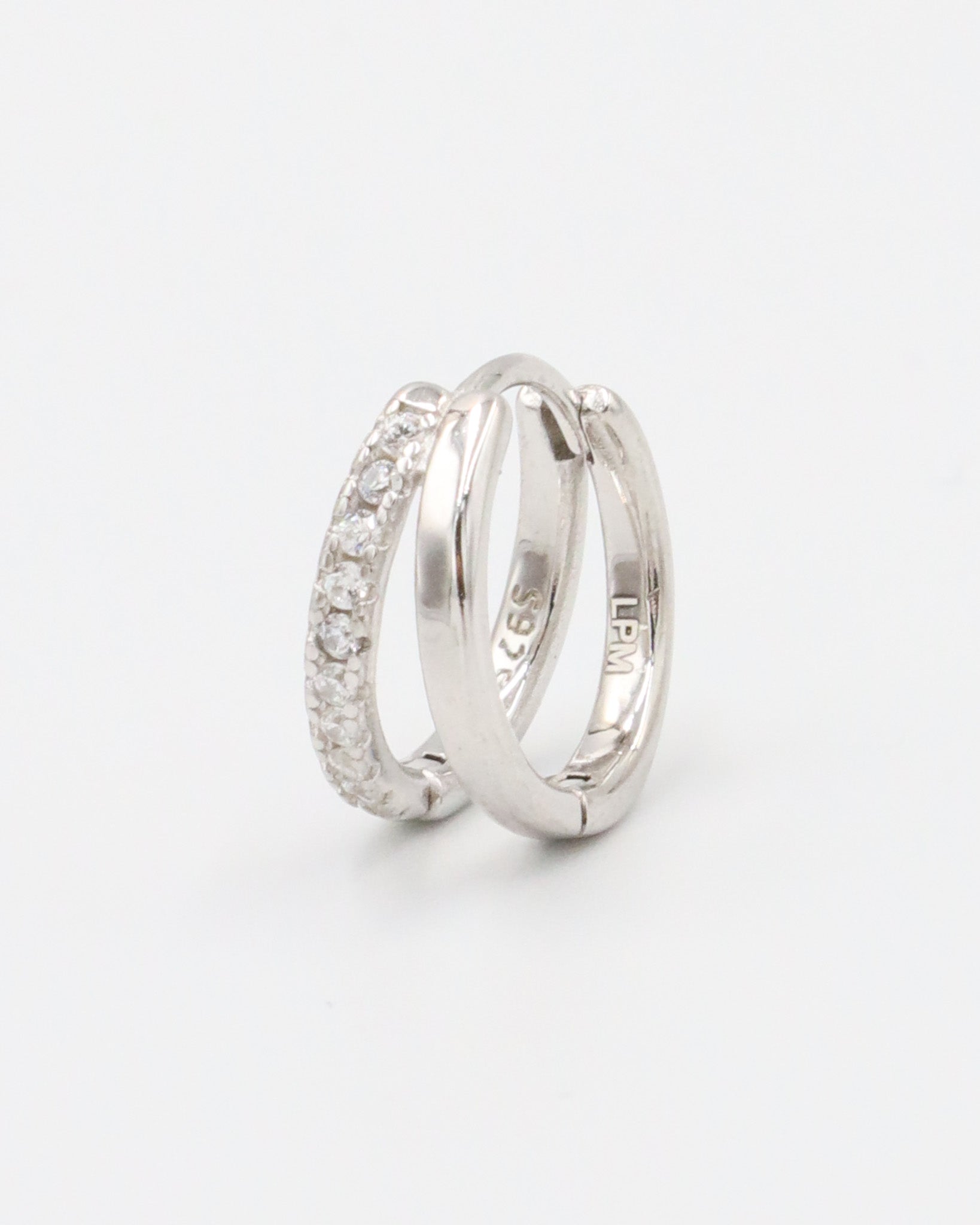 A single silver hoop earring with a hinged clasp closure, featuring a row of small clear stones on the hoop.
