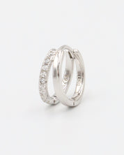 A single silver hoop earring with a hinged clasp closure, featuring a row of small clear stones on the hoop.