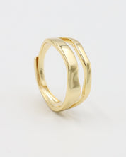 A single gold-colored ring with a smooth, curved design on a white background.