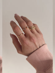 A single gold-colored ring with a smooth, curved design worn on a hand.