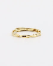 A gold-colored band ring with a textured surface on a white background.