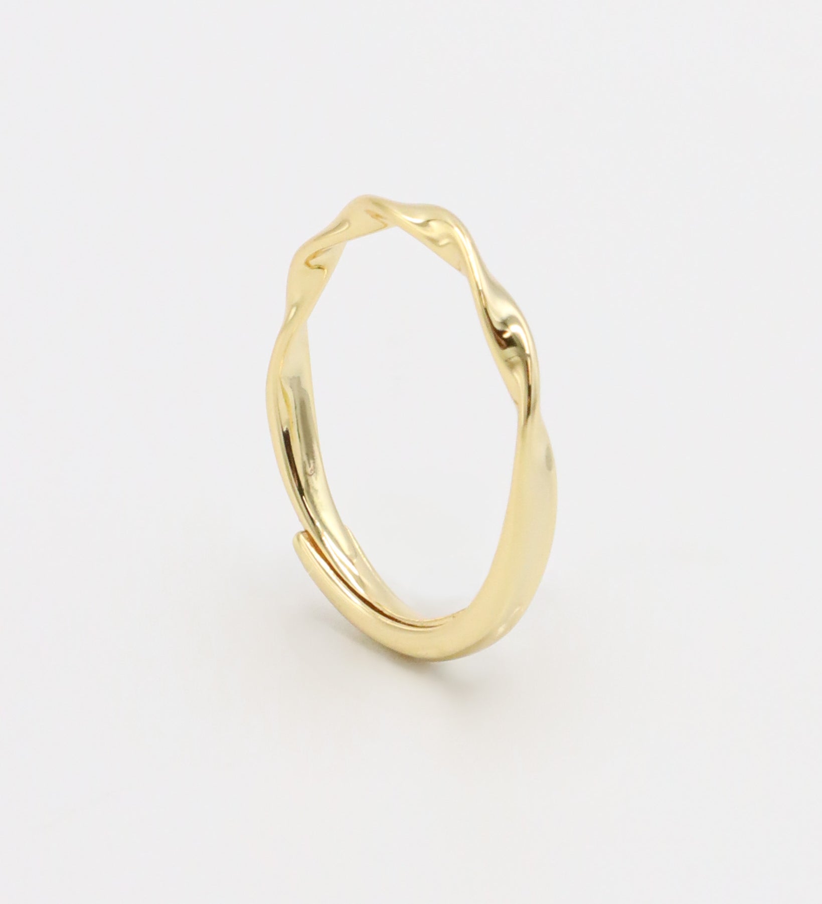 A gold-colored band ring with a textured surface on a white background.