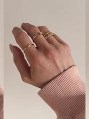 A gold ring with a simple, modern design worn on a hand.