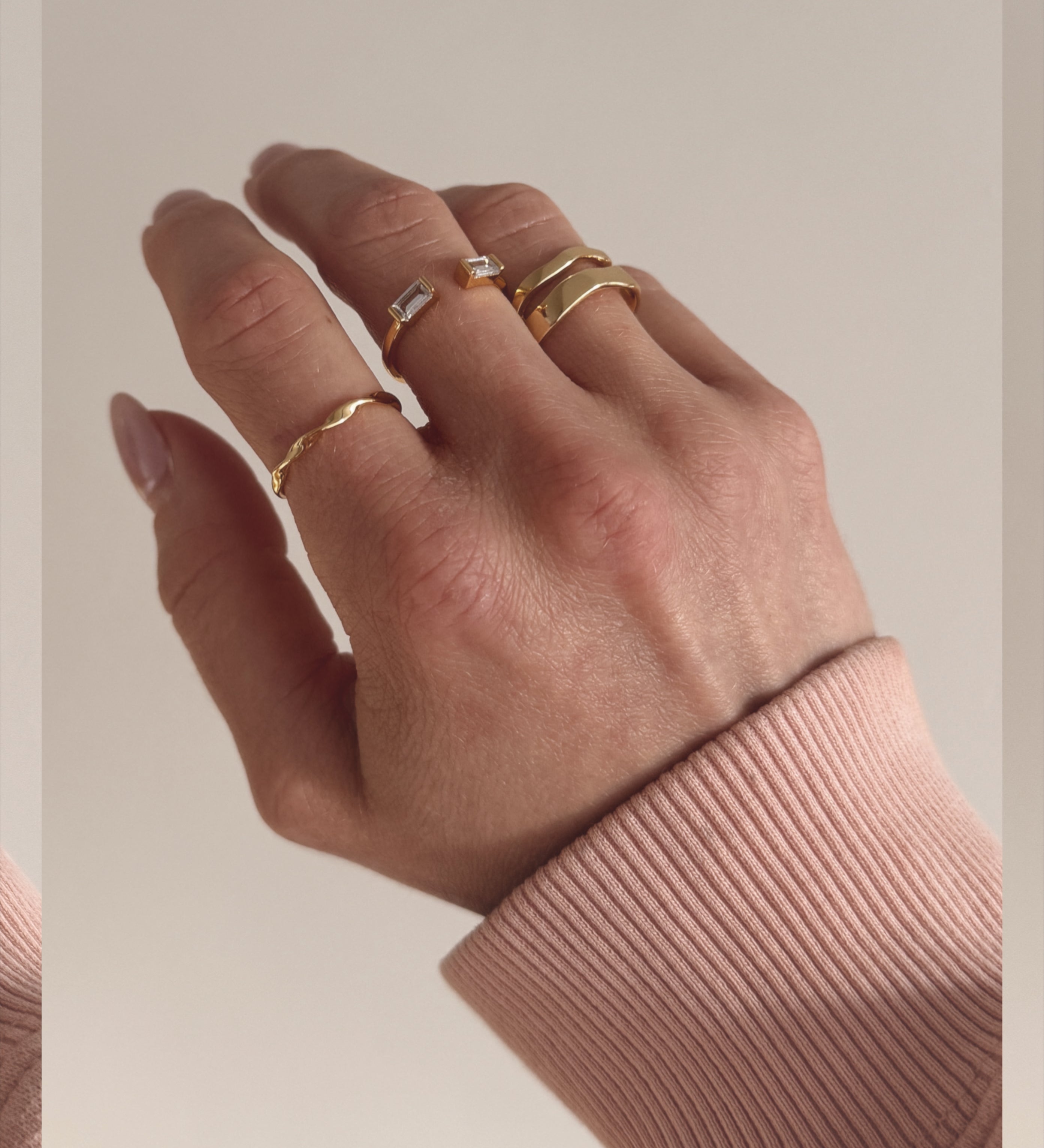 A gold ring with a simple, modern design worn on a hand.