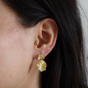 Close-up of an ear wearing the Miri Earrings in the lobe and the Lu gold hoop in the tragus piercing.
