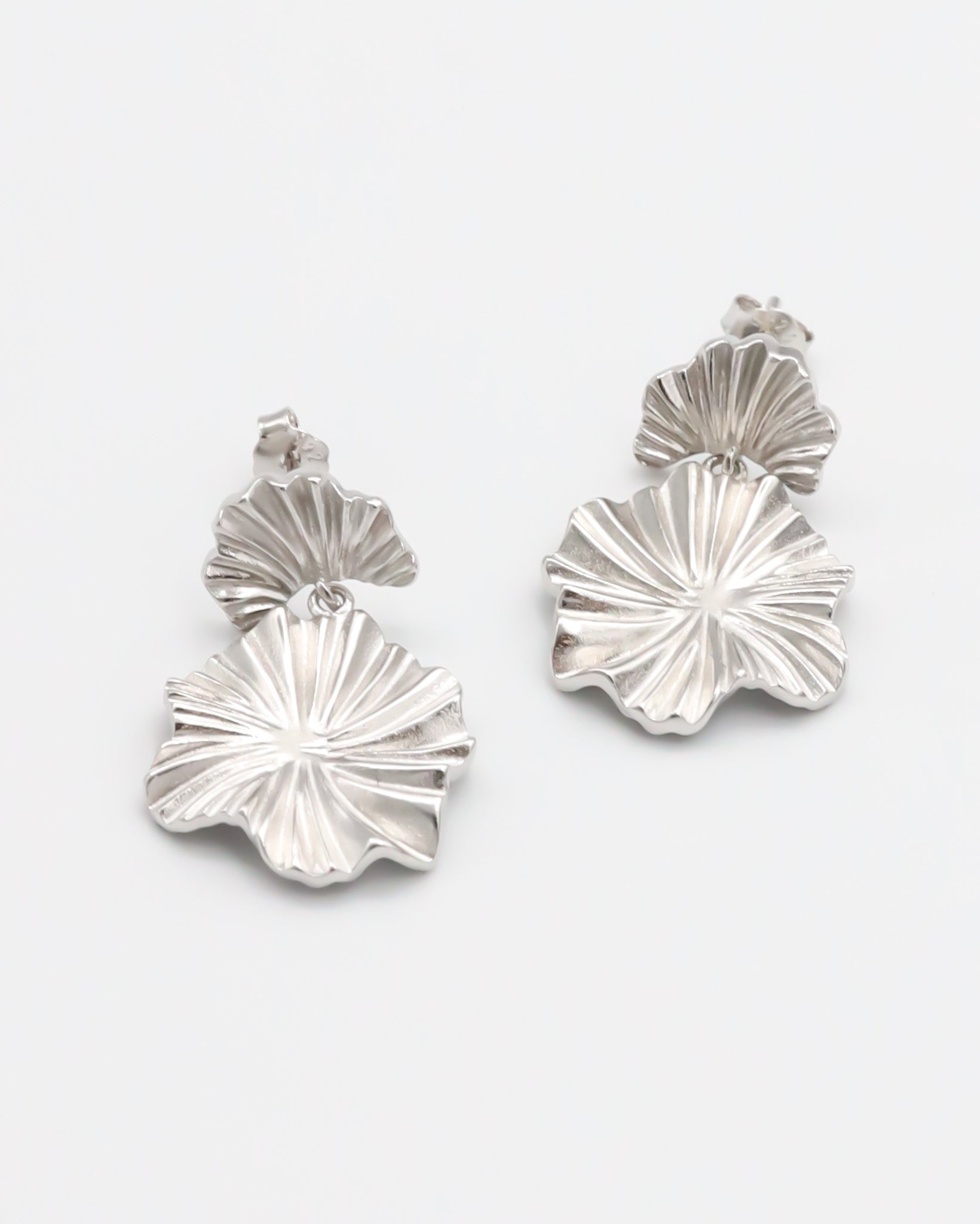 A pair of silver stud earrings with a butterfly clasp and floral design