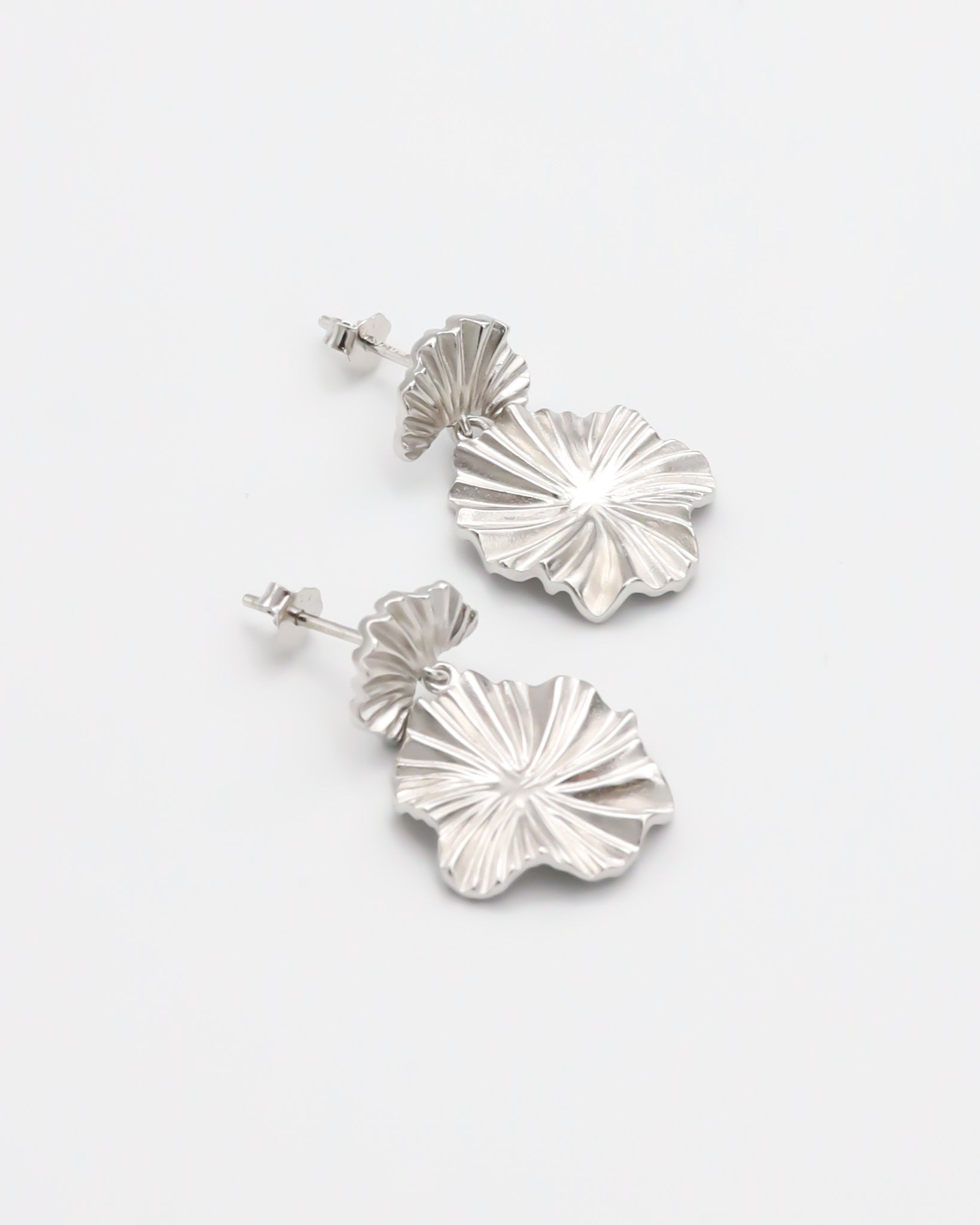 A pair of silver stud earrings with a butterfly clasp and floral design
