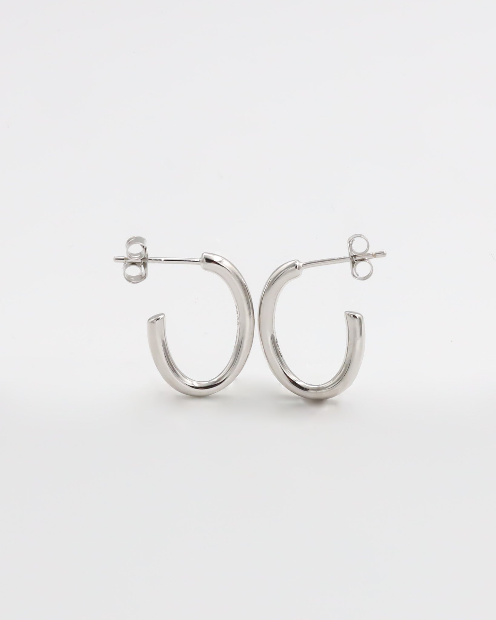 A pair of silver hoop earrings with a butterfly clasp closure on a white background.