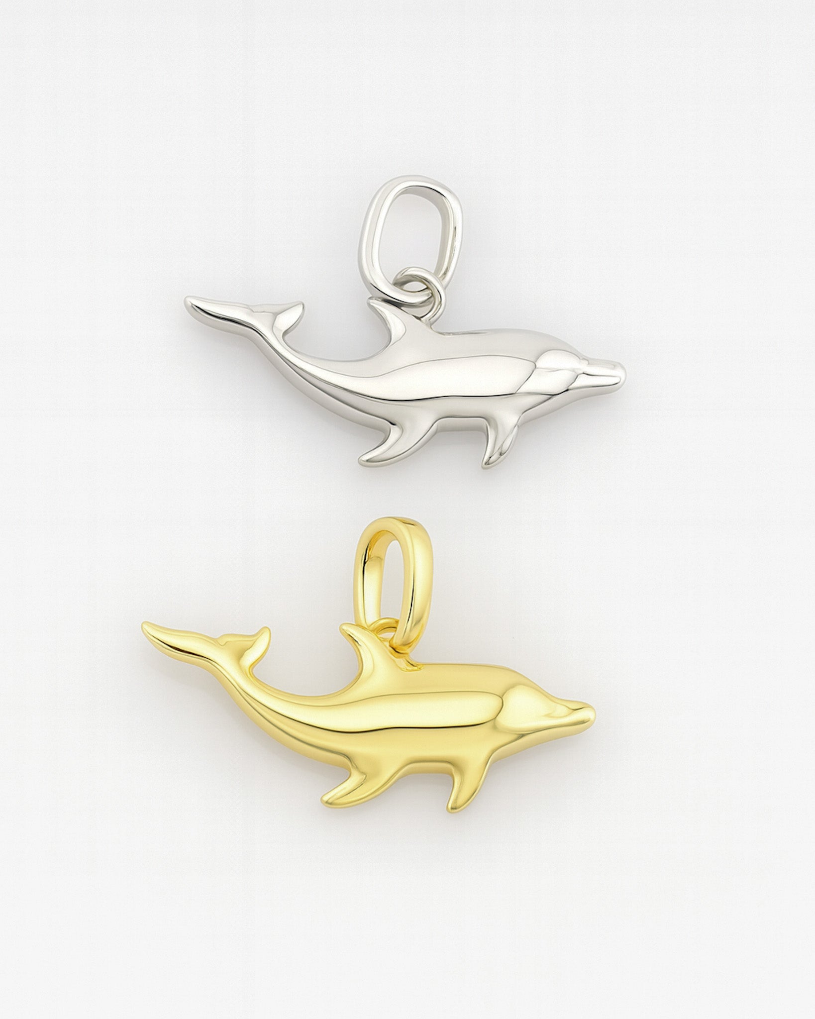 Gold and silver dolphin pendants on a white background