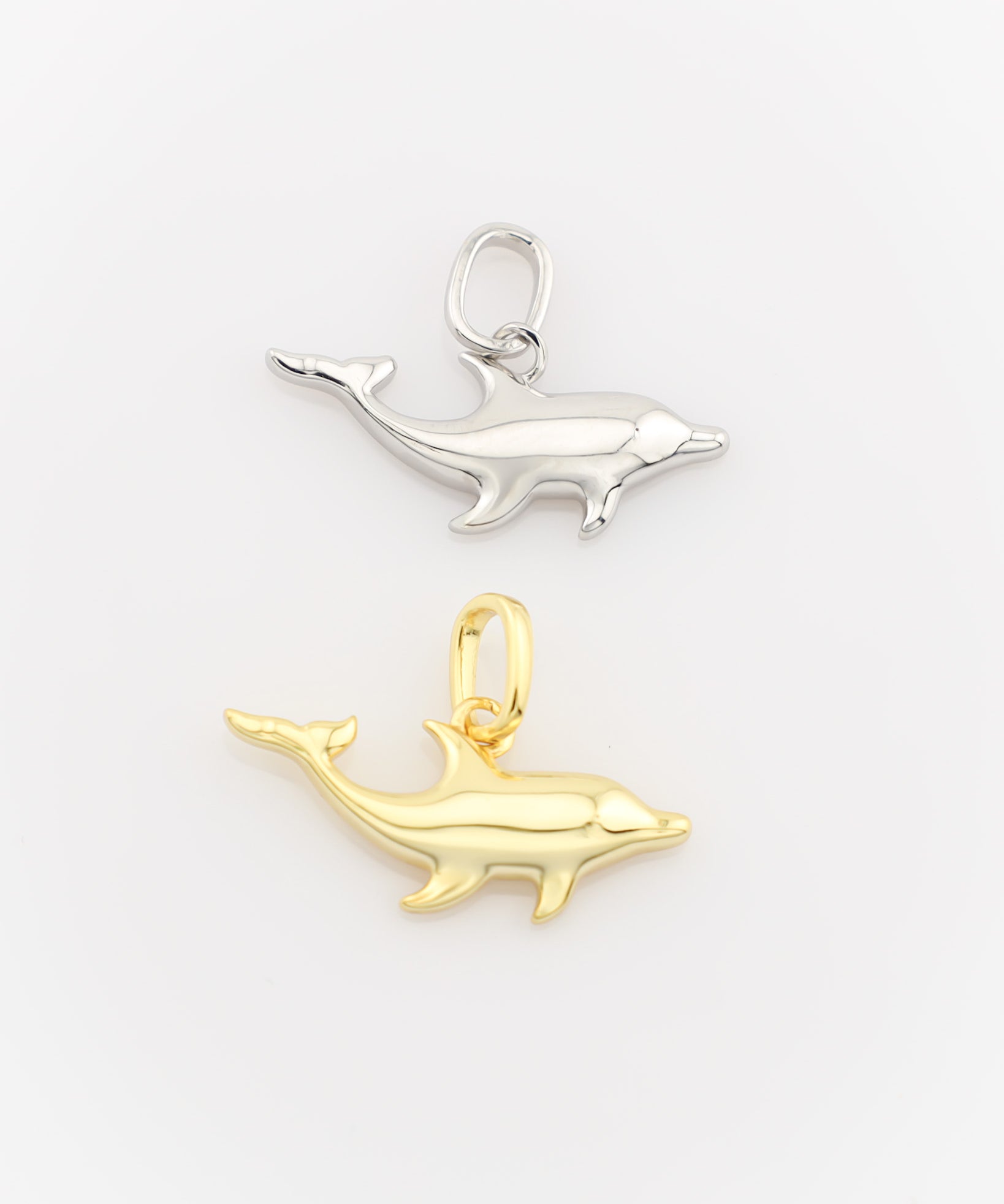 Gold and silver dolphin pendants on a white background