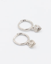A silver-colored ring with a small heart-shaped charm attached to it, displayed against a white background.