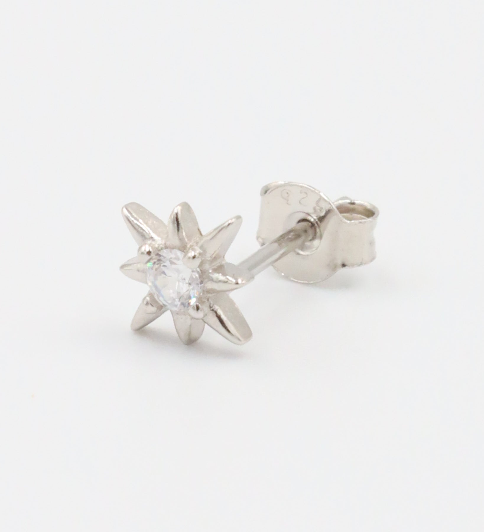A single silver star-shaped stud earring with a small central gemstone, displayed against a white background.