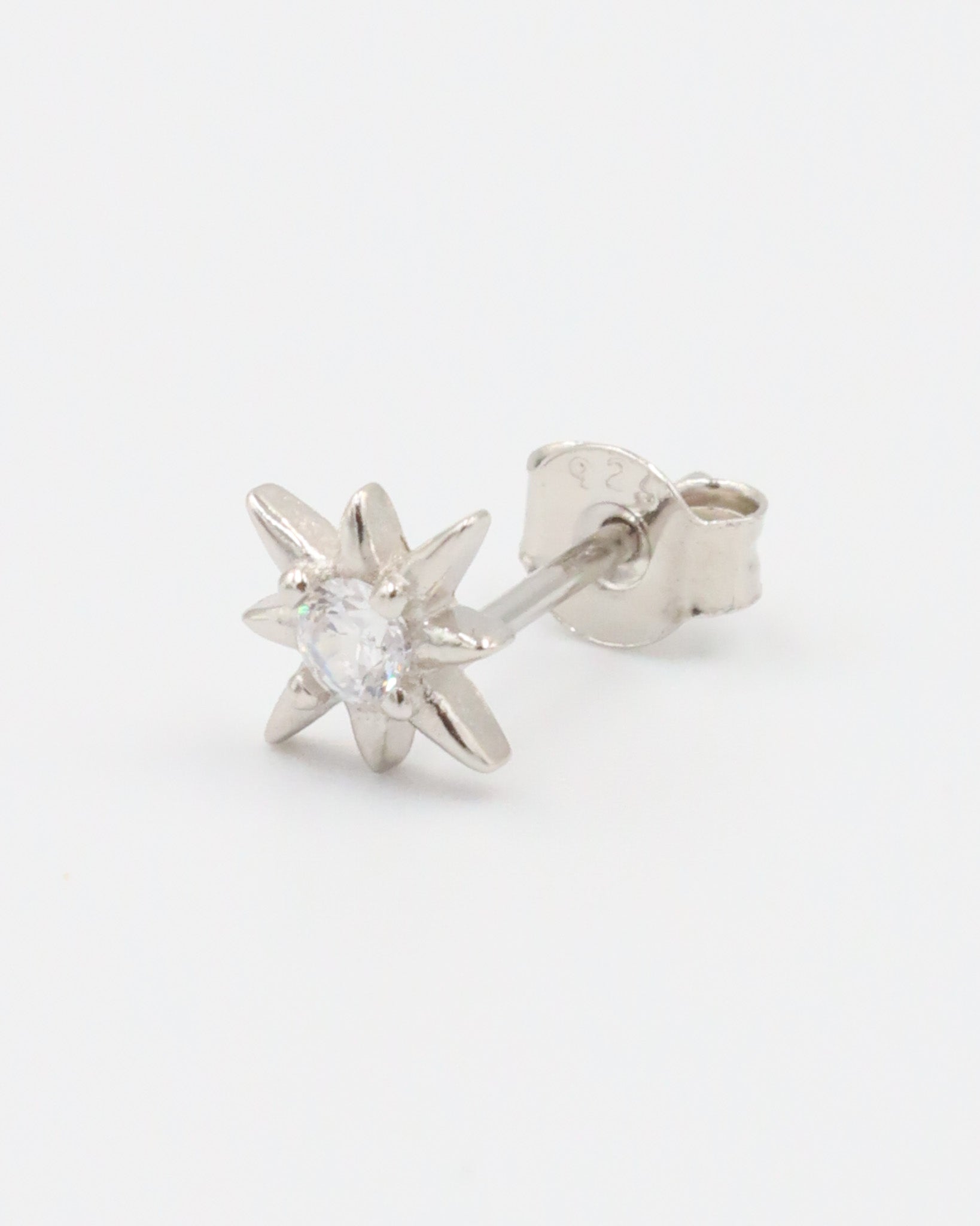 A single silver star-shaped stud earring with a small central gemstone, displayed against a white background.
