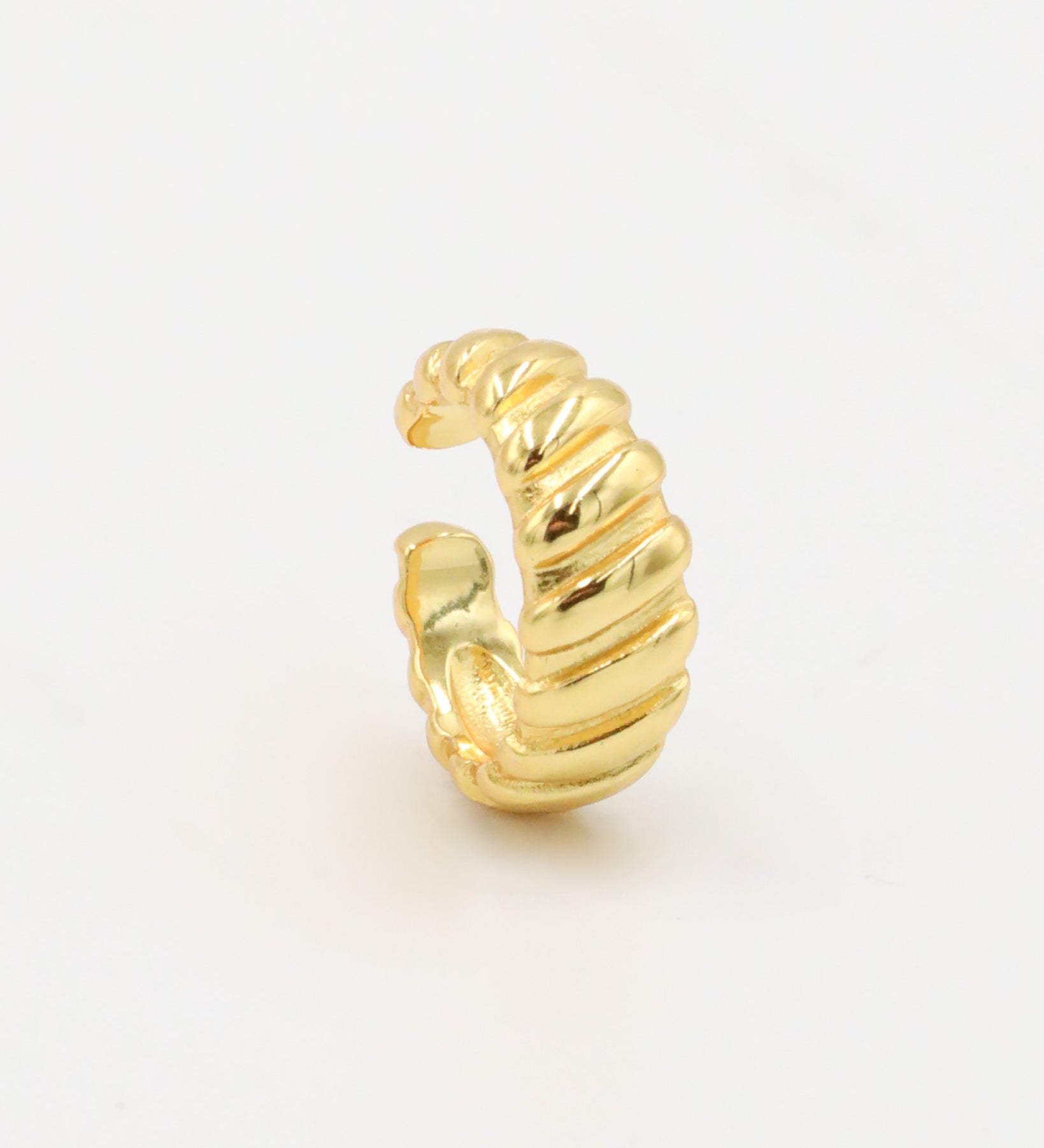 A gold-colored ear cuff with a textured, curly-like appearance on a white background.