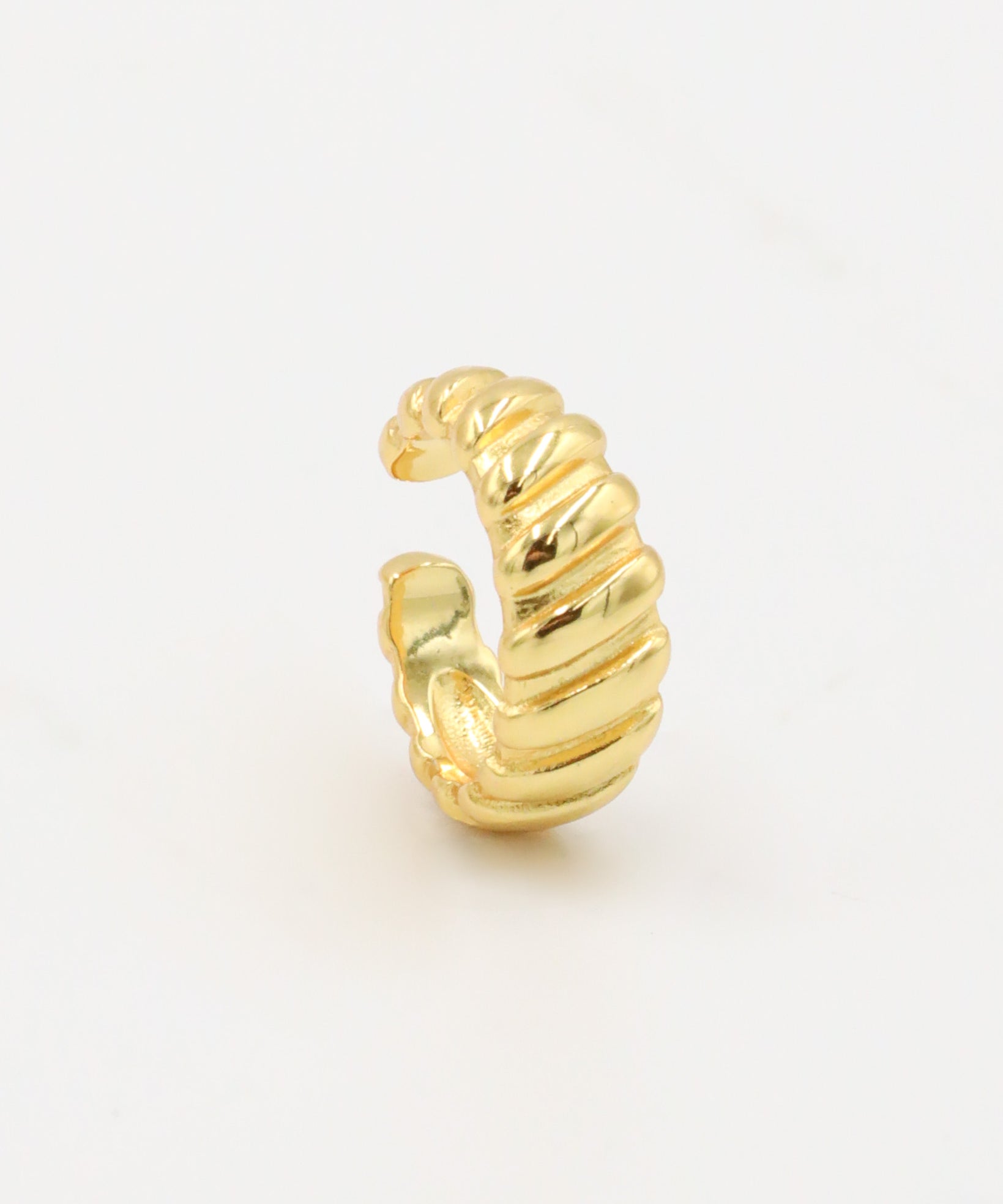 A gold-colored ear cuff with a textured, curly-like appearance on a white background.
