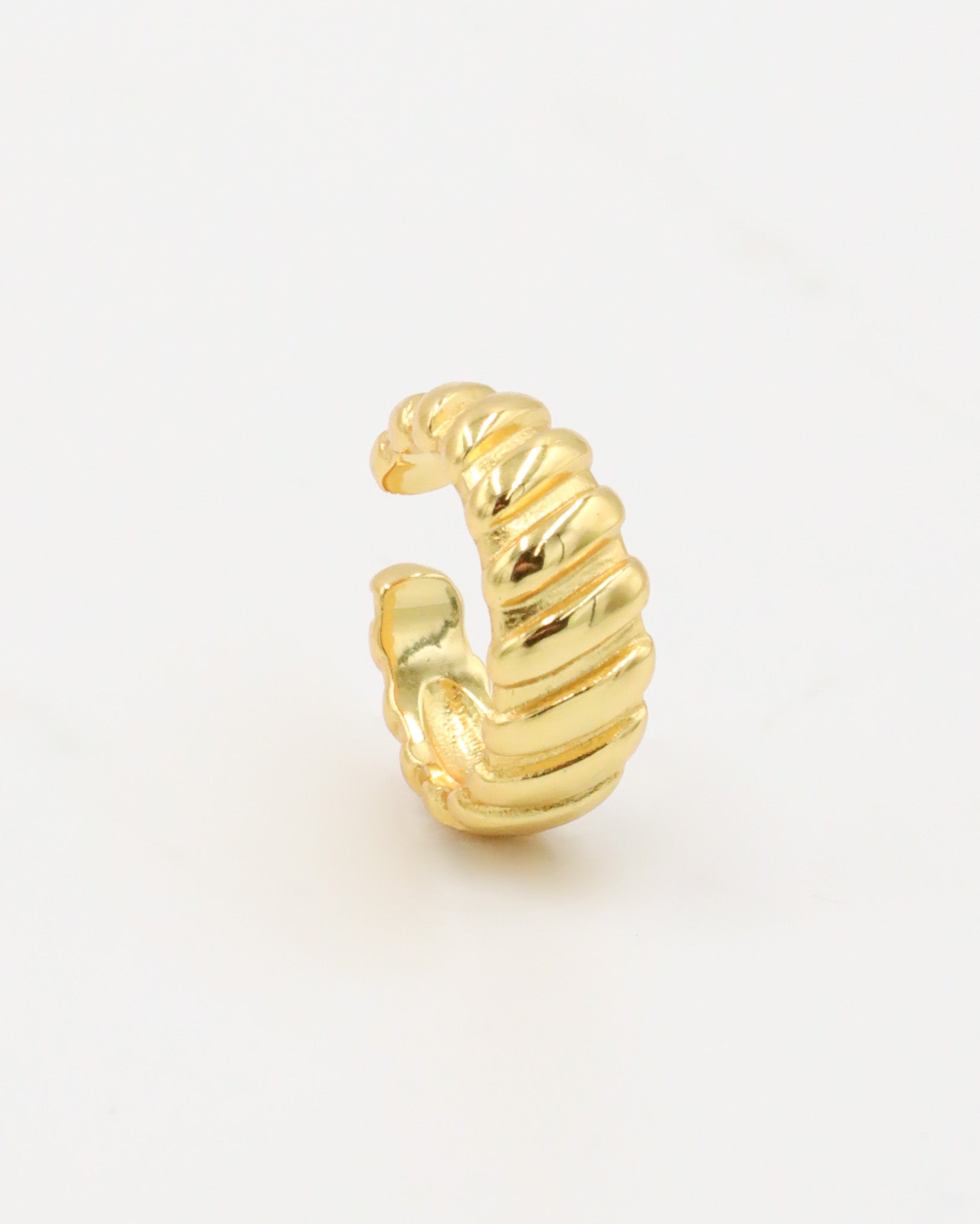 A gold-colored ear cuff with a textured, curly-like appearance on a white background.