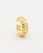 A gold-colored ear cuff with a textured, curly-like appearance on a white background.