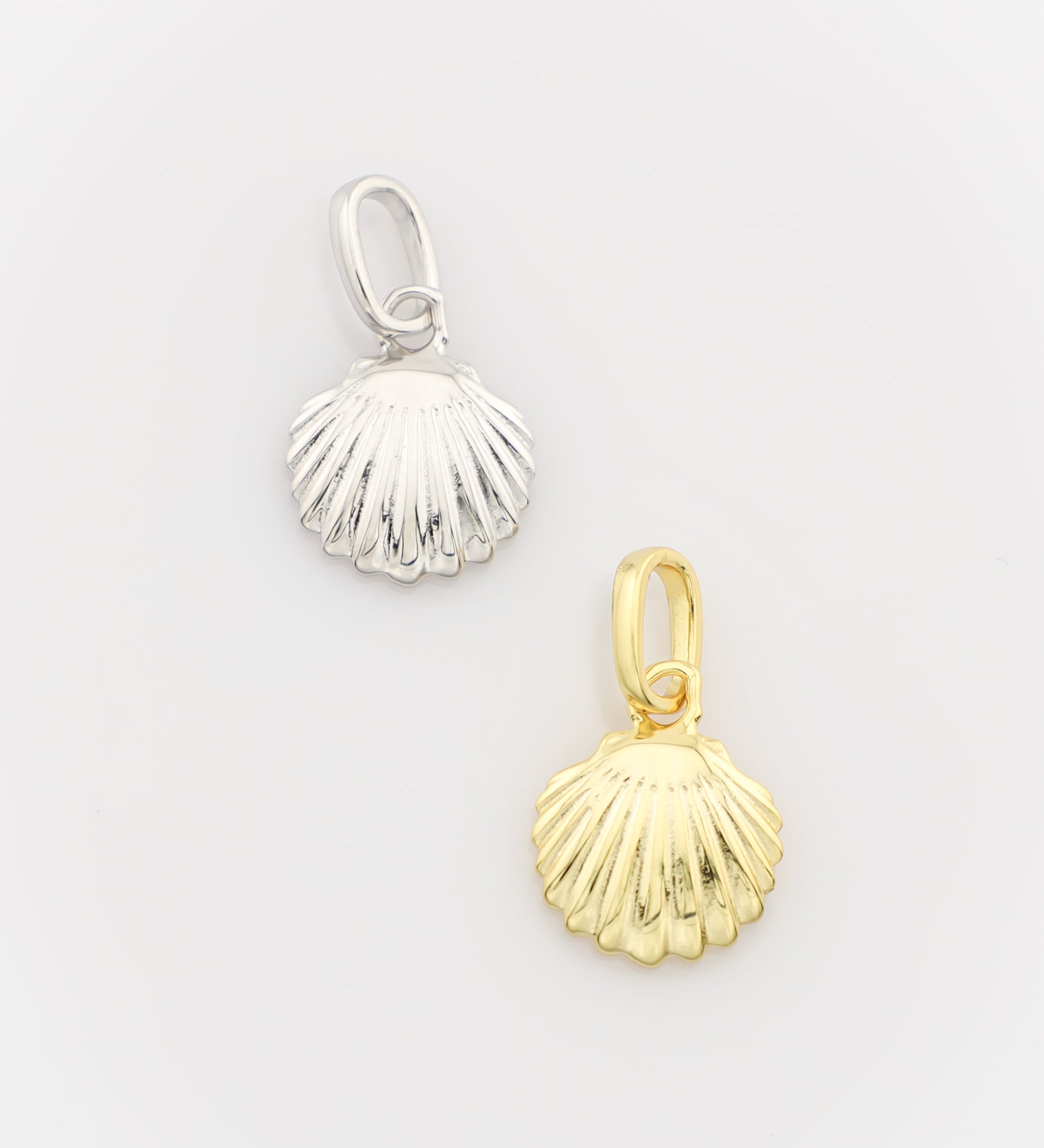 Silver and gold shell-shaped pendants on a light gray background