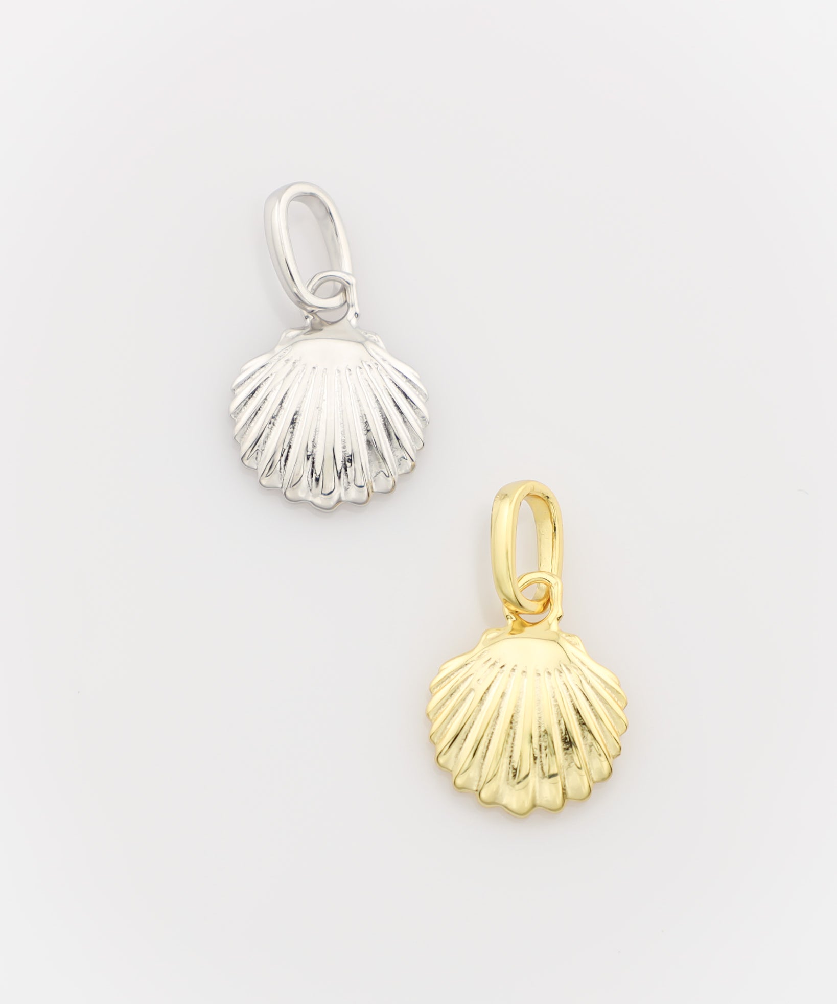Silver and gold shell-shaped pendants on a light gray background