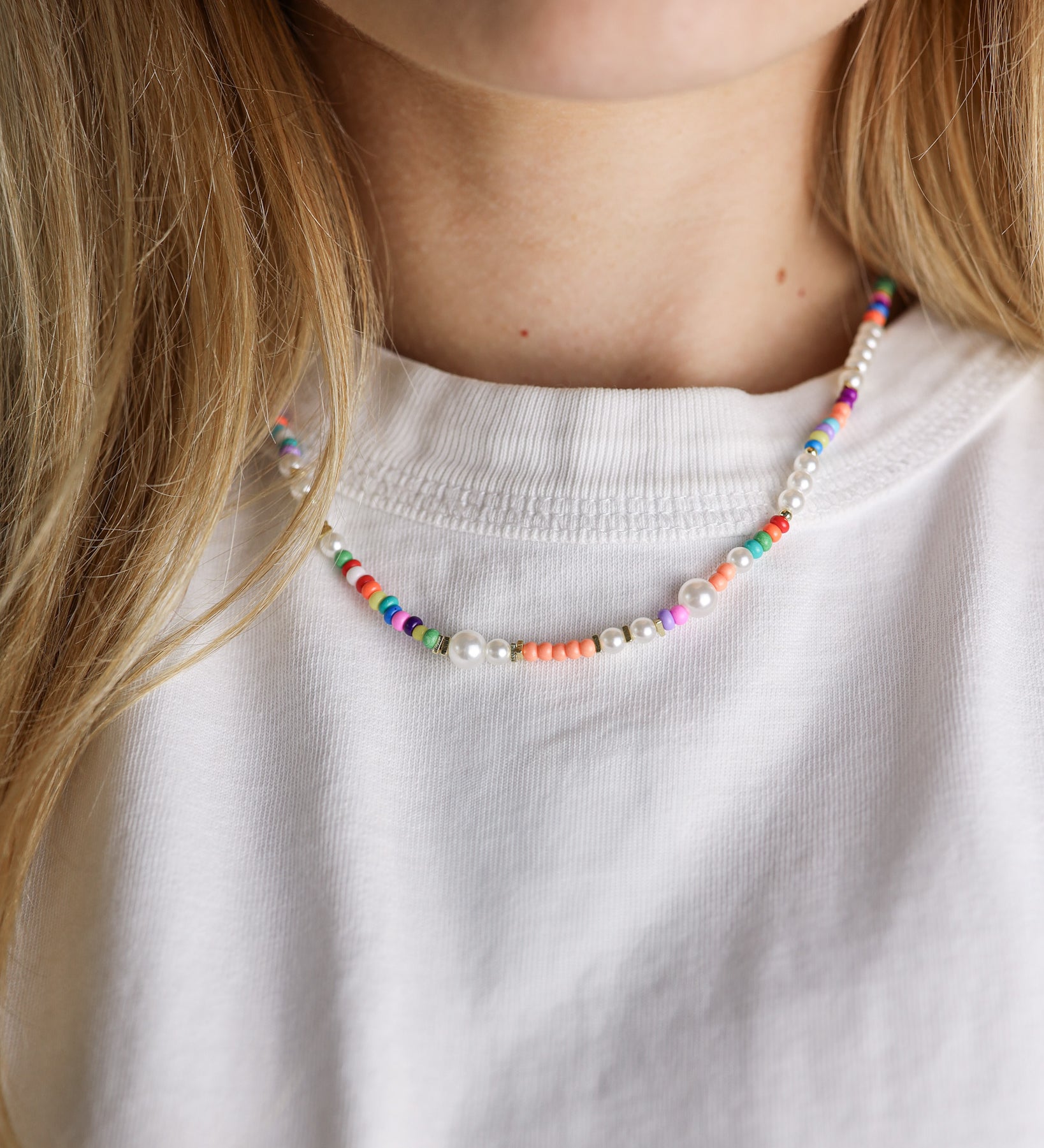 Colorful beaded necklace worn by a person with a white shirt
