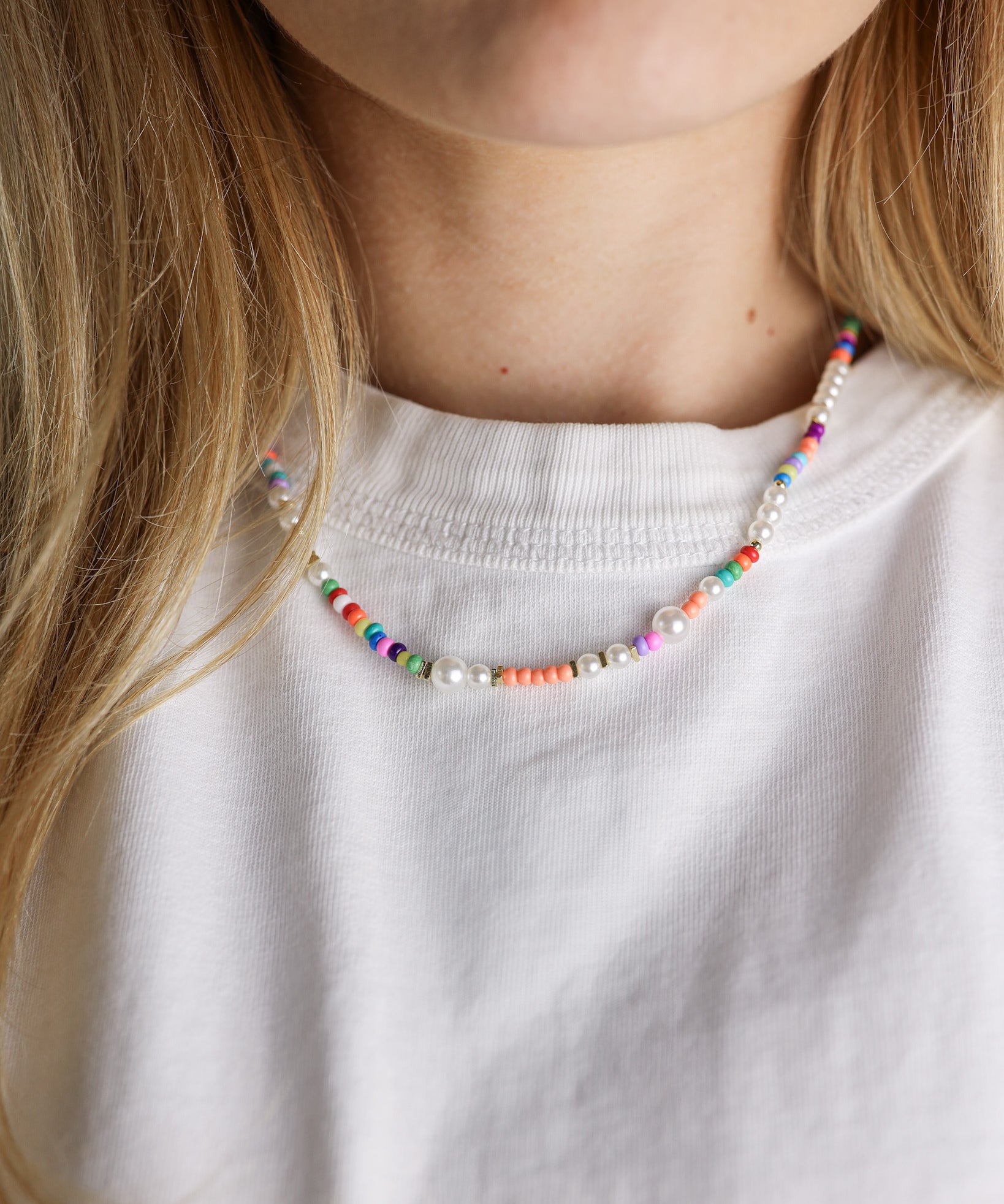 Colorful beaded necklace worn by a person with a white shirt
