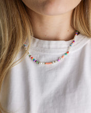 Colorful beaded necklace worn by a person with a white shirt