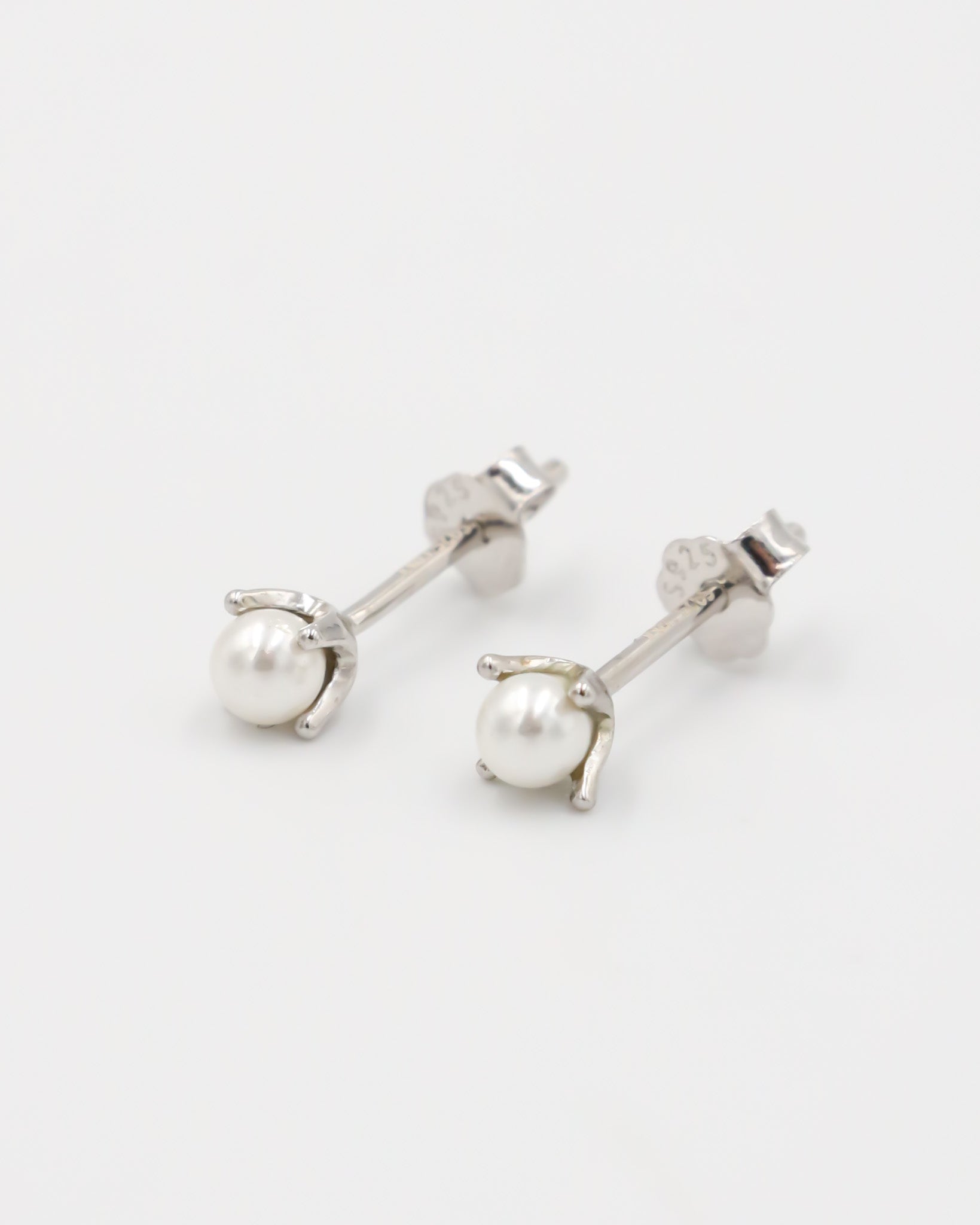 A single silver stud earring with a pearl bead and butterfly clasp.