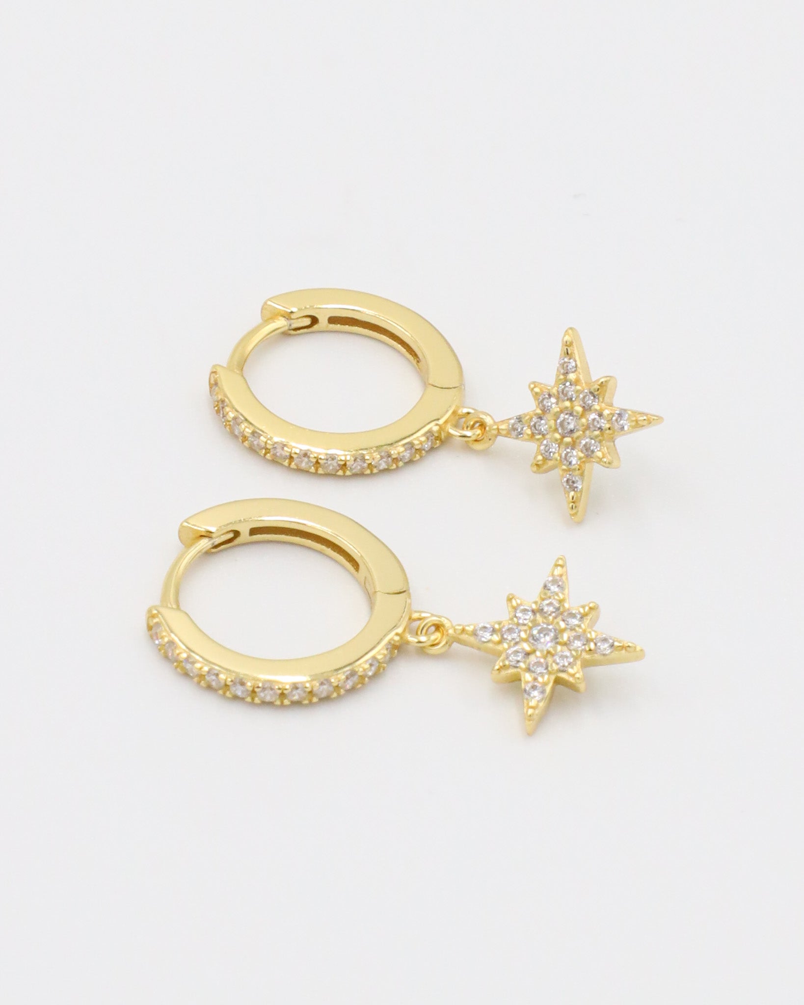 A pair of gold-plated sterling silver hoop earrings with pavé zirconia stones and a star-shaped pendant, detailed with additional zirconia.