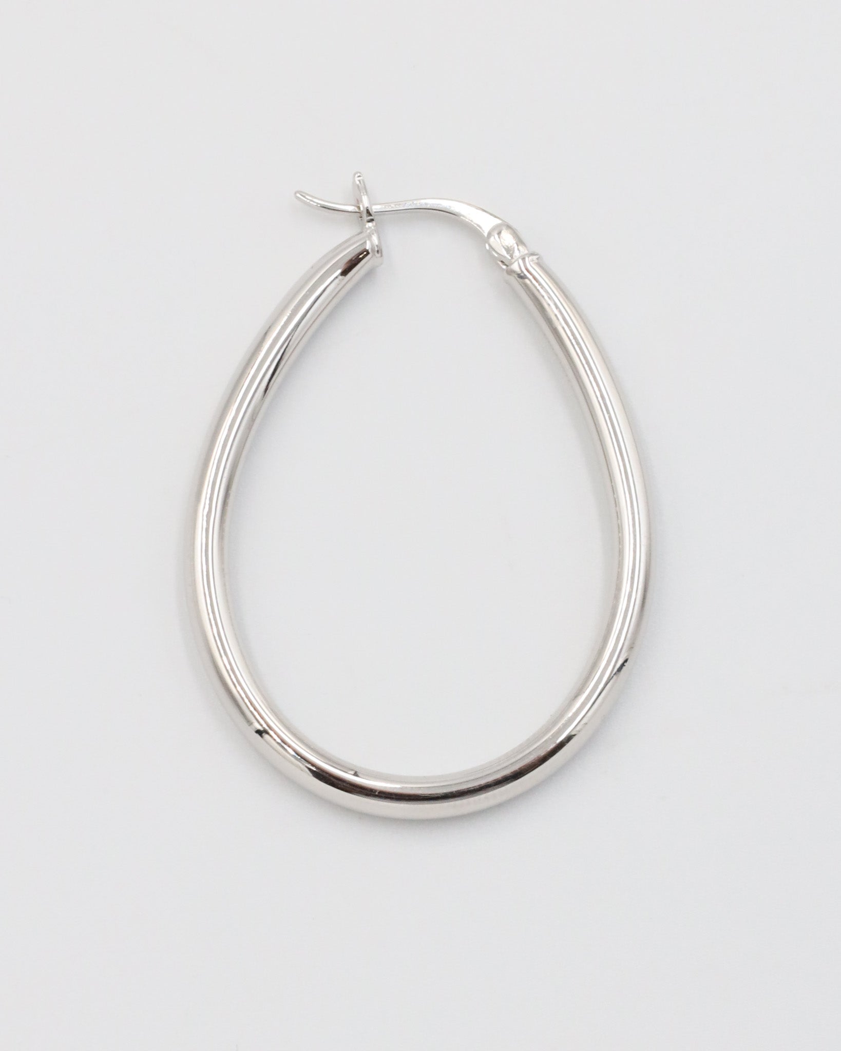 A single silver creole earring with a latch back clasp on a white background.