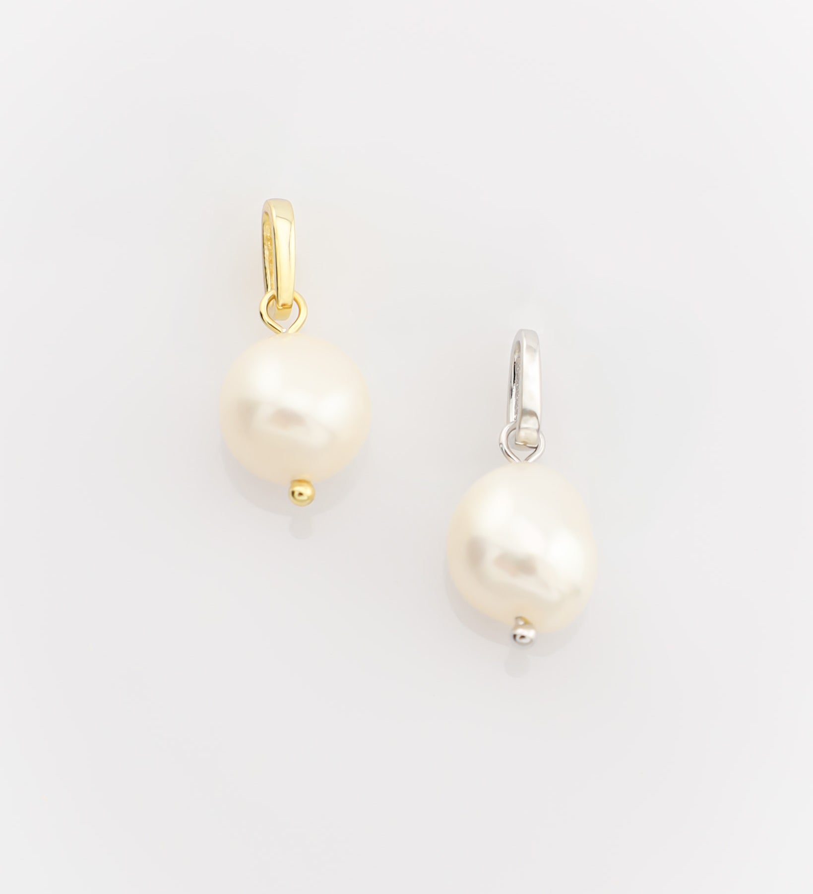 Two pearl earrings on a light gray background