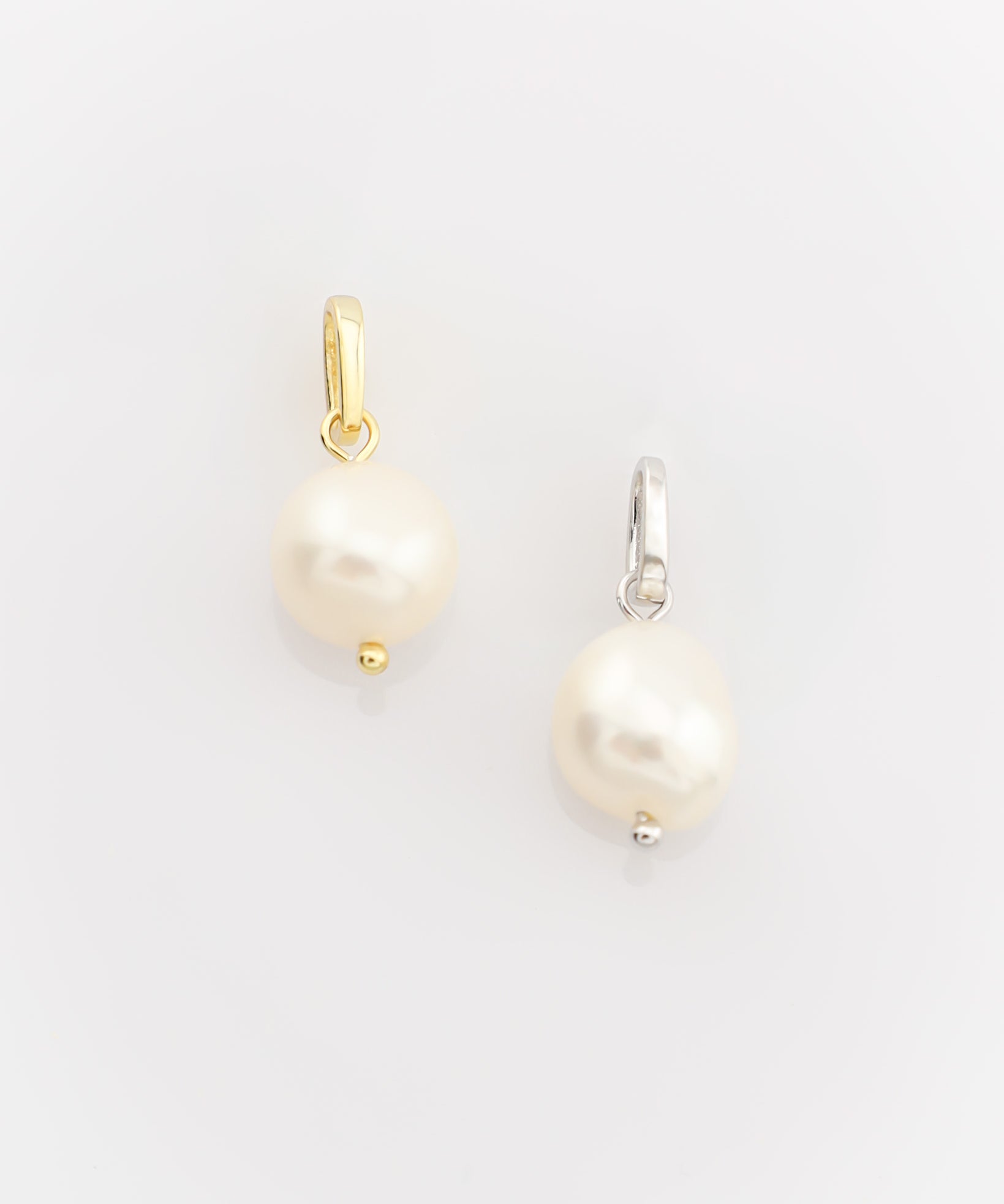 Two pearl earrings on a light gray background