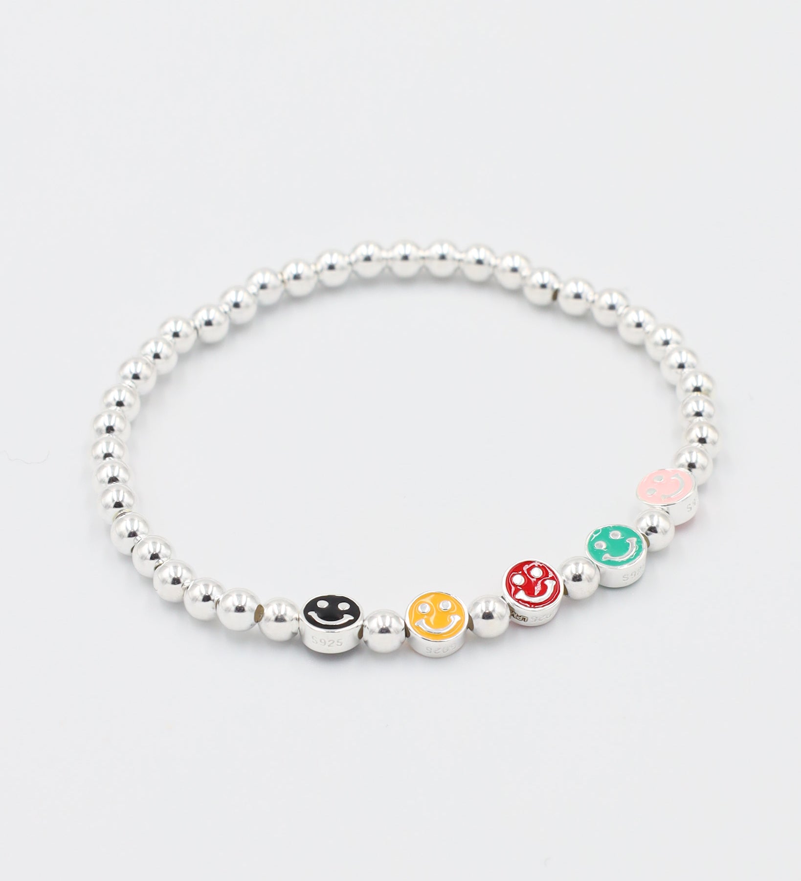 Angled view of adjustable sterling silver bracelet featuring multi-colored smiley face beads and round silver beads.